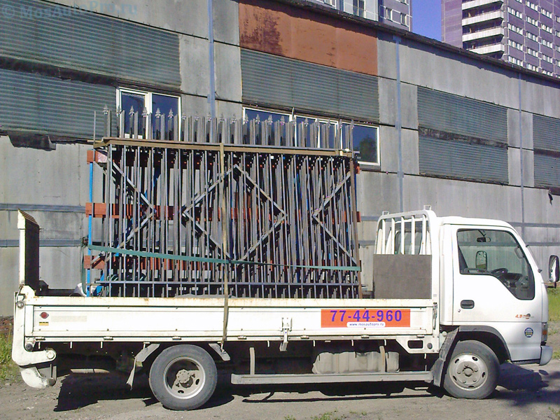 Перевозка секций металлического забора из профильной трубы на машине с гидробортом в центре Москвы.
