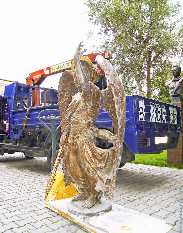 Перевозка скульптуры Архангела с мечем машиной с краном манипулятором.