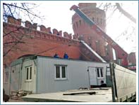 Погрузка офисно-жилого сборного модуля с помощью крана манипулятора на территории Московского Кремля возле Москворецкой башни.